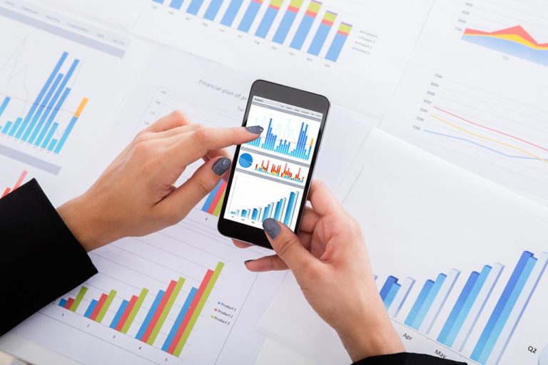 | Epidemic Marketing A person holding a phone that displays a graph presentation; on the table various printed graphs and charts were placed