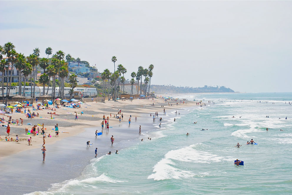Crowds flock at the beach located in Carlsbad, CA