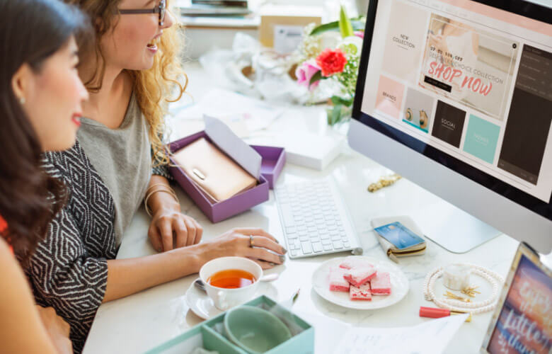 Two women working on shop now banners in a desktop computer