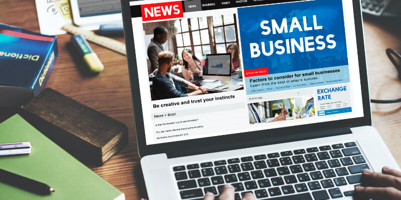 An open laptop placed on a wooden table with Small Business flashed on screen