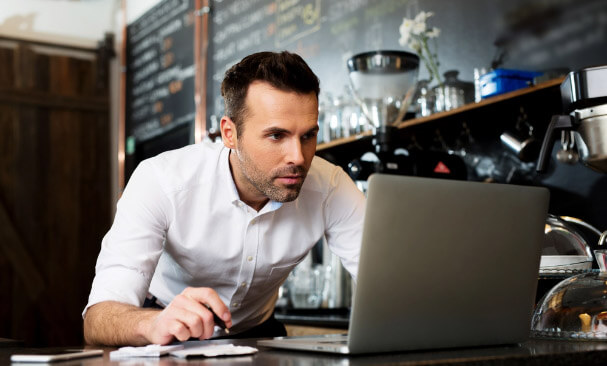 Man looking at a laptop screen inside a coffee shop