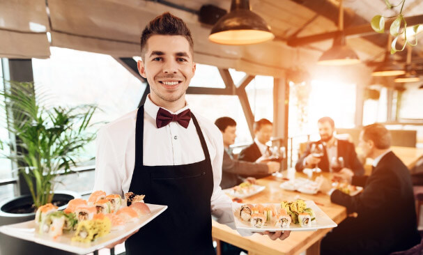 Waiter in a restaurant holding sushi on trays in both hands