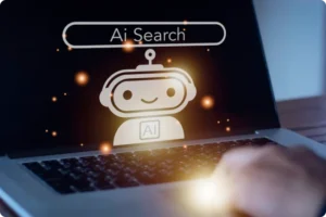 Close-up of a laptop screen displaying a cartoon robot with "Ai" on its chest and a search bar labeled "Ai Search" above it, with a hand typing on the keyboard.